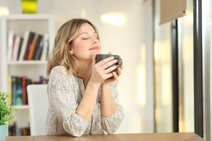 Portrait of a woman breathing and holding a coffee mug at home